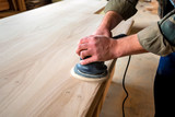 Fototapeta  - Man sanding wood with orbital sander in a workshop