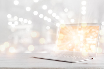 Laptop computer with glowing screen on table over abstract background