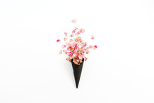 Black Ice Cream Waffle Cone With Dry Pink Roses Petals Isolated On White Background. Flat Lay, Top View Flower Concept.