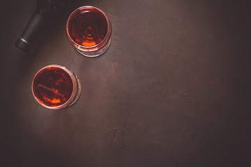 Two wineglasses with red wine and lying bottle on brown wooden desk