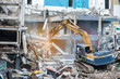 © theeraphong - Worker controlling backhoe demolishing old buildings. Demolition site with pile of rubble and bulldozer at Bangkok site.