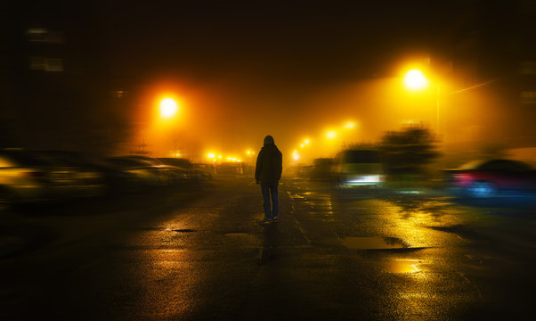 Fototapete - a mysterious man stands alone in the street, among cars in an empty city, walks the night street, dreams