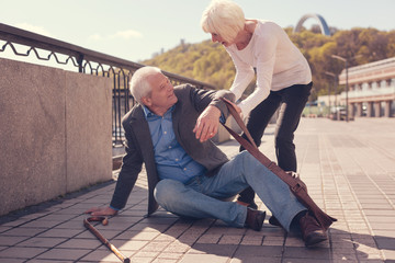 Courteous senior lady helping a passer-by get up