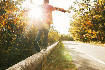 boy walking along the road fence. child keeps balance on the log. copy space for your text