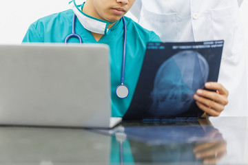 Doctors use laptop computer researching the symptoms of a patient from x-ray at head bone. concept of medical consult and treatment skull.