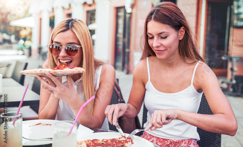Zdjęcie XXL Czas pizzy. Młode dziewczyny je pizzę w kawiarni. Konsumpcjonizm, styl życia