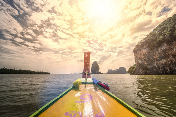Wall Mural - A long tail boat is sailing in the Ao Phang Nga (Phang Nga Bay) National Park at sunset. Phang Nga is one of the southern provinces (changwat) of Thailand.
