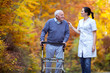 Nurse helping elderly senior man. Senior man using a walker with caregiver outdoor