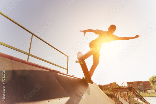 Papel de parede Teen skater hang up over a ramp on a skateboard in a skate park
