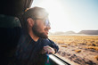 © AlejandroMCB photo & film/Stocksy - Young man leaning on the window of a car enjoying the view while traveling at sunset