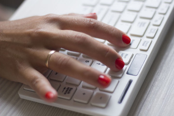 Female hands typing on white computer keyboard