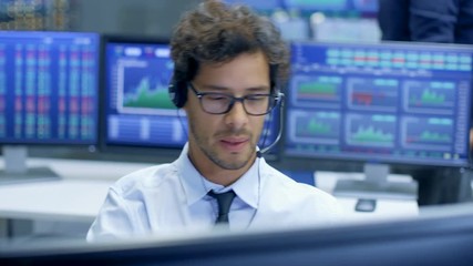 Poster - Broker Making Sales with a Headset with His Multi-Ethnic Team of Stock Traders at the Stock Exchange Firm Office is Busy Selling and Buying Bonds and Shares. Displays Show Relevant Graphs and Numbers.