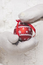Hand With Gloves Holding A Christmas Ornament
