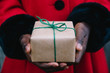 © Gabriel (Gabi) Bucataru/Stocksy - African American girl's hand in red coat holding a wrapped present