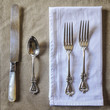 © Holly Clark/Stocksy - Beautiful silverware on a neutral tablecloth.