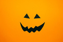 Paper Jack O'Lantern Face On Orange Background. Halloween Concept. Flat Lay