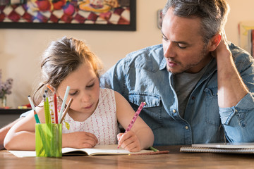 Wall Mural - A father helps his little daughter to do her homework for the school.