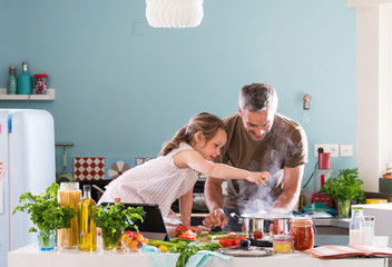 Daddy and his little daughter cooking a recipe in the kitchen