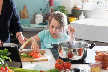 Wall Mural - A little girl cooking a recipe in the kitchen with her mother