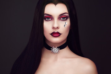 Halloween Vampire Woman portrait. Beautiful Glamour Fashion Sexy Vampire Lady with long dark Hair, beauty make up and Costume