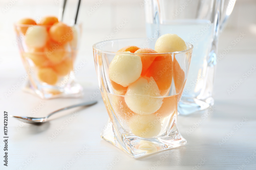 Glass of delicious cocktail with melon balls on table