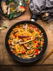 Wall Mural - Tasty vegetarian fried noodles pan with vegetables and  creamy pasta sauce on wooden background, top view