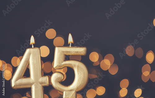 Photographie Gold number 45 celebration candle against blurred light background