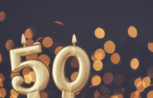 Gold Number 50 Celebration Candle Against Blurred Light Background