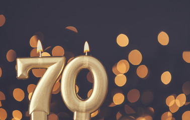 Wall Mural - Gold number 70 celebration candle against blurred light background