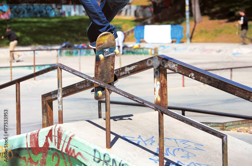 Plakat młody skater skacze na balustradzie w skateparku / miejski skater robi sztuczki na balustradzie w skateparku