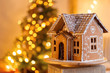 gingerbread house over defocused lights of Chrismtas decorated fir tree