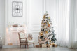 © prescott09 - Classic white christmas interior with new year tree decorated. Fireplace with grey chair, clocks on the wall and presents under the tree
