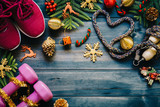 Fototapeta  - Exercise, Fitness and Working Out Merry Christmas and Happy new year concept, dumbbells, sport shoes, skipping rope or jump rope  in heart shape with Christmas decoration items on wood background. 