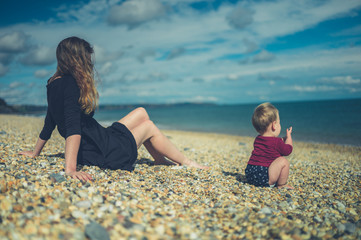 Wall Mural - Young mother sitting on beach with her baby