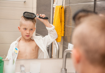 Wall Mural - Little boy brushing his hair with a comb in the bathroom