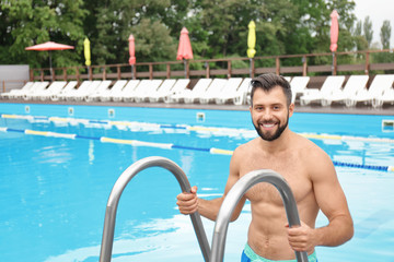 Wall Mural - Handsome young man getting out of swimming pool