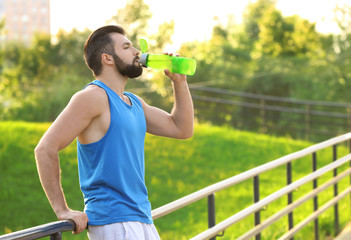 Wall Mural - Sporty young man drinking water in park