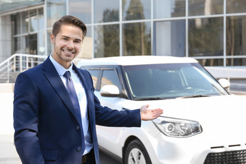 Salesman standing near new car outdoors