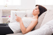 © Prostock-studio - Young woman using a mobile phone on sofa.