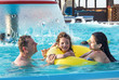 Father and children playing in the swimming pool at the day time. People having fun outdoors. Concept of happy family.