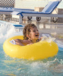 Little boy swimming in the pool with rubber ring, having fun in swimming pool.