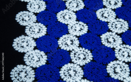 Plakat ciepła wełnista tkanina z białymi i niebieskimi kwiatami, koła na czarnym tle