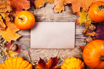 Thanksgiving border or frame with orange pumpkins and colourful leaves on wooden background with copyspace.