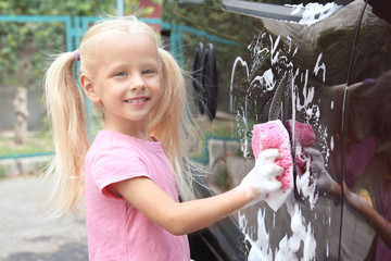 Sticker - Adorable little girl washing car with sponge outdoors