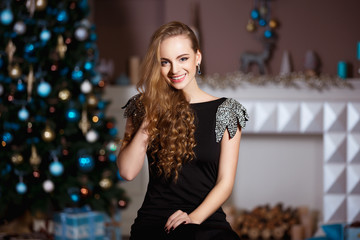 holidays, celebration and people concept - young woman in elegant dress over christmas interior back