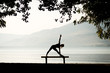 Silhouette of woman doing triangle yoga pose on a bench