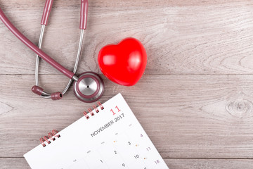 Wall Mural - Check heart Concept : Red heart, Calendar and stethoscope on brown wooden table background