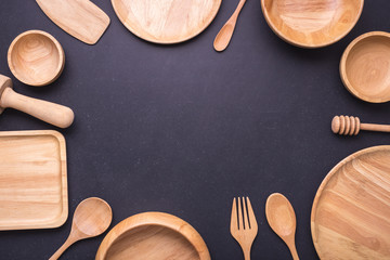 Wall Mural - Collection of new wooden kitchen utensil, bowl, plate, spoon, dish. Studio shot on black table. With free space for text or design