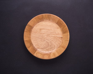 Wall Mural - Bright empty wooden dish/bowl on black stone board background