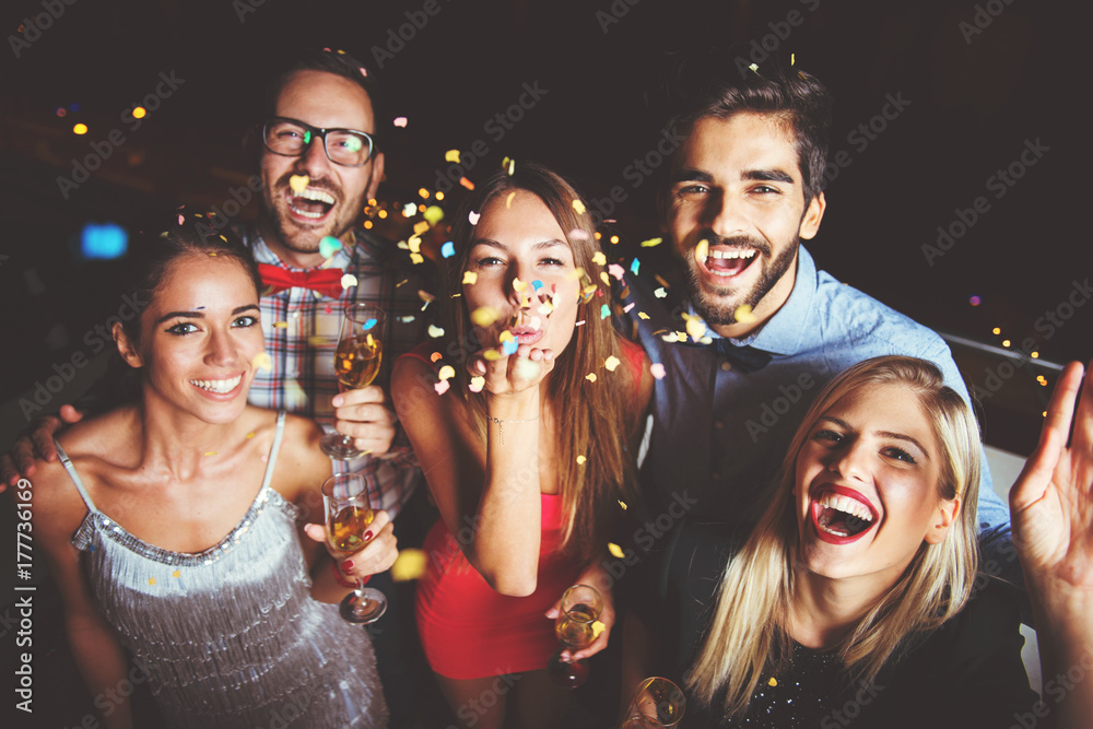 Group of people having a party, blowing confetti  - obrazy, fototapety, plakaty 